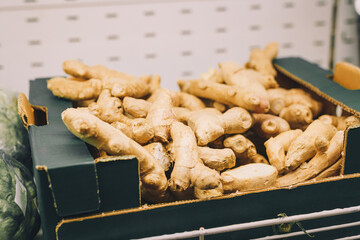Ginger roots in box on supermarket shelf, grocery department. Food, vegetables, hot spices for bakery and beverages