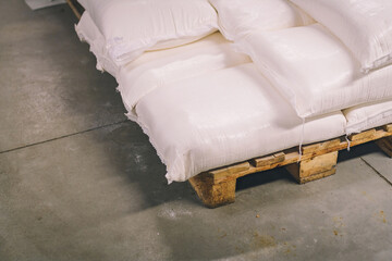 White sacks of some groats, sugar or flour lying on wooden pallets in food store, shop, mall, warehouse. Wholesale