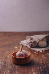 Garlic in pot, wooden kitchen background. Anti-fungal, anti-cancer, anti-inflammatory vegetable, herbal medicine. Copy space, vertical shot