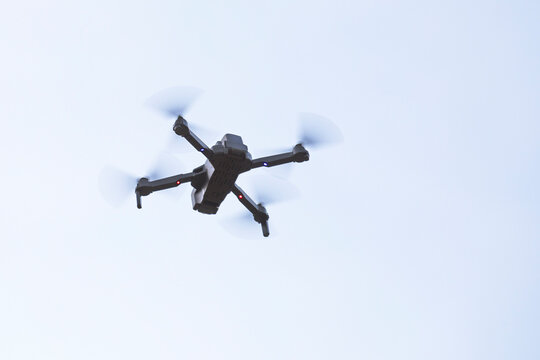 Drone en vol dans ciel bleu avec h&eacute;lices en rotation.