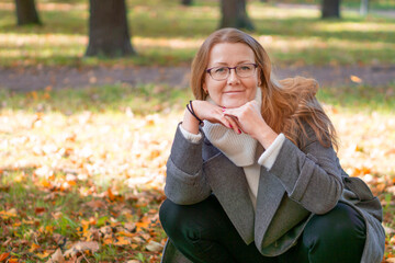 Photo of a cute blonde lady, yellowed falling leaves, a walk and a beautiful unforgettable scent of autumn, city park, on the street.