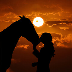 Silhouette of a young girl with horse giving him a kiss over a red sunset background © hibrida