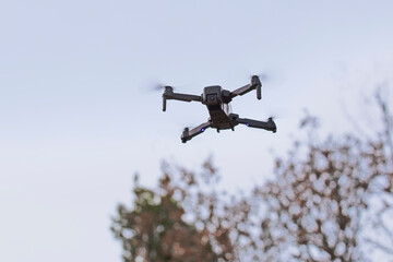 Drone en vol stationnaire au-dessus des arbres dans la campagne. - obrazy, fototapety, plakaty