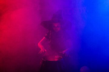Little witch child cooking potion in the cauldron on Halloween.