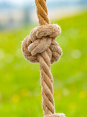 Knotted sports rope hanging from crossbar of horizontal bar