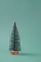 Beautiful fake miniature Christmas tree not decorated over a green background. Small Christmas tree. Copy space, front view