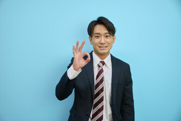 指でOKを作るスーツ姿のアジア人男性ビジネスマン