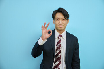 指でOKを作るスーツ姿のアジア人男性ビジネスマン