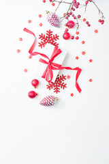 Flat lay frame with red berries, christmas red balls and gift box on a white background. Merry christmas card and copy space for your text