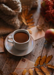A cup of coffee on a wooden background, apples in a bag are on the table.