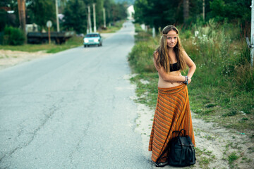 A hippie girl voting near the road. Hitchhiking trips.