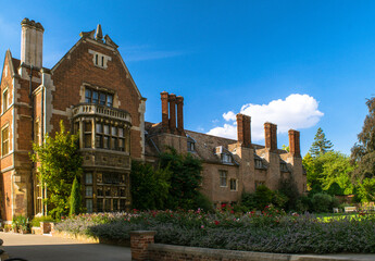 Facade of historical bricked Christ's College building with a garden and tall chimney stacks at Cambridge England