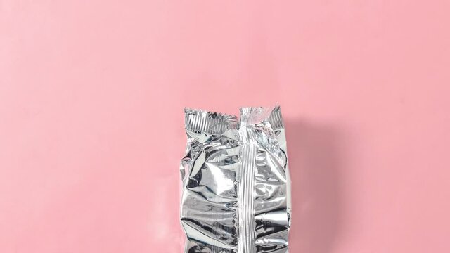 Stop motion animation. Unpacking shortbread cookies from a package on a pink background. Top view.