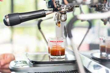 Close-up of espresso pouring from coffee machine. coffee extraction from professional coffee machine with bottomless filter and , barista preparing coffee at cafe