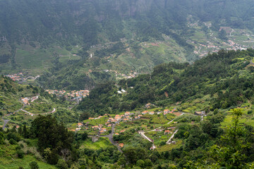 Fototapeta premium Aerial view on small city Sao Vicente - Chapel on the hill, huge mountains on background. Madeira island, Portugal.