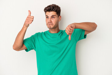 Young caucasian man isolated on white background showing thumbs up and thumbs down, difficult choose concept