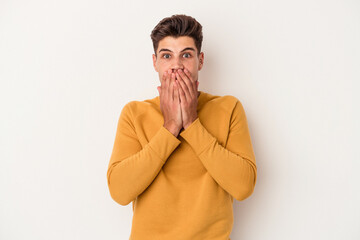 Young caucasian man isolated on white background shocked covering mouth with hands.