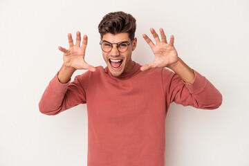 Young caucasian man isolated on white background showing claws imitating a cat, aggressive gesture.