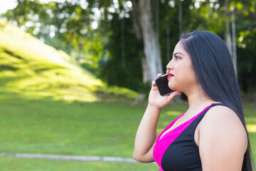 Hispanic woman talking on the cell phone in the park