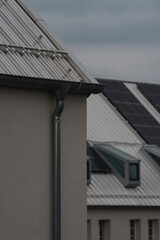 a metallic roof of a house with a house with metallic roof and solar panels and windows in the background