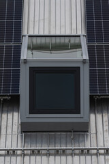 a modern window in a top floor with solar panels on the roof