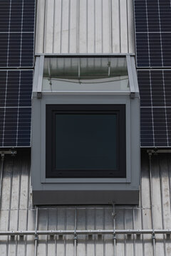 a modern window in a top floor with solar panels on the roof