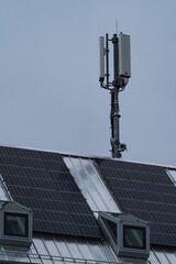 a radio mast on a roof, solar panels are on the roof