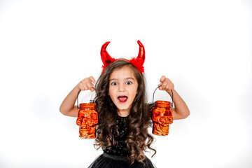 Halloween kids. Curly little girl in a witch costume with skull lanterns on a white studio...