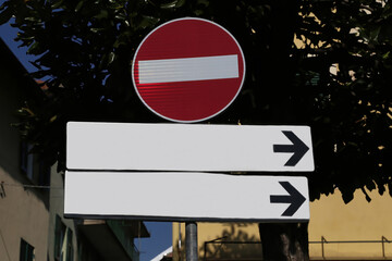 Red road sign with no entry and under two white copy space signs with direction arrow to the right