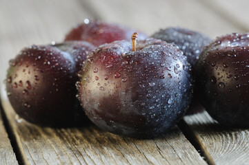 Ripe plums of a round shape close-up. Washed fruits with water drops. Selective focus, natural light