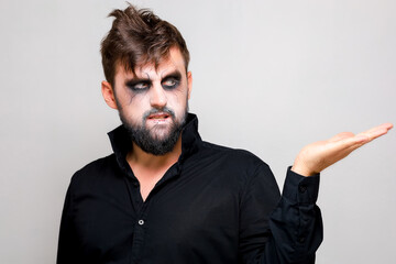 a man with a beard and undead makeup on Halloween holds his hands in front of him