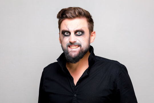 undead makeup for October 31 on a bearded man who shows teeth