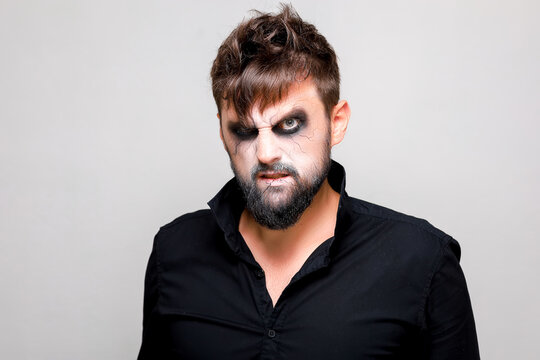 undead-style makeup on a bearded man who looks from under his brows and grimaces