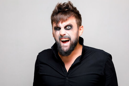 undead-style makeup on a bearded man who looks from under his brows and grimaces