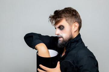A bearded man with undead-style makeup opens a black box for Halloween