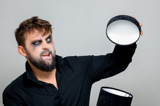 a bearded man with makeup for Halloween opens a black gift box