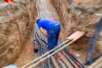 Blurred electrical technician in trench connecting high voltage