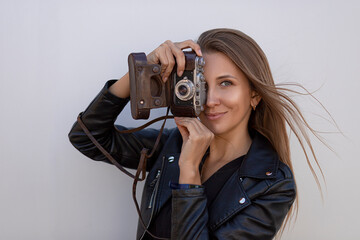 Portrait of a beautiful woman photographer with a retro camera isolated on a grey wall.