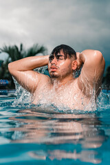 Joven gay saliendo del agua de una piscina 