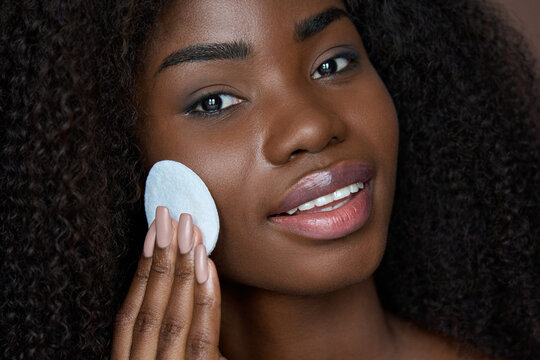 Pretty African Ethnic Black Young Woman Holding Cotton Pad Removing Face Make Up With Makeup Remover Cleanser On Brown Background. Oily Skin Care Treatment, Cleaning Skincare Routine Concept.