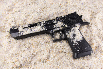 Black pistol lying in the sand