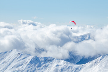 Fototapeta na wymiar Paraglider is flying over the mountains in Gudauri, Georgia