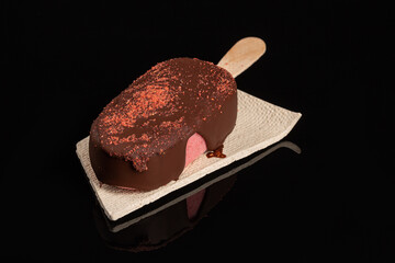 Eskimo strawberry ice cream dark chocolate icing on black background
