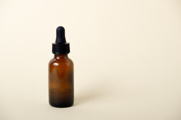 Essential serum oil in amber dropper bottle. Serum glass bottle with pipette on beige background. Natural organic liquid medicine or cosmetic oil.