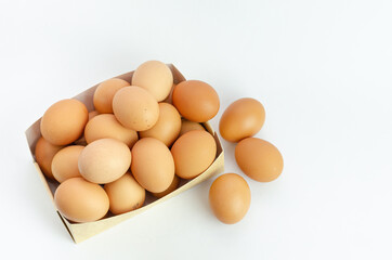 Eggs inside brown ready cardboard box, on white background. Fresh eggs for the kitchen. Copy space.