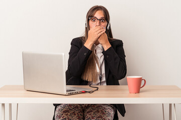 Young caucasian woman doing telecommuting isolated on white background shocked covering mouth with hands.