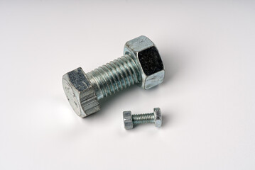 The largest and smallest bolts with nuts on a white background.