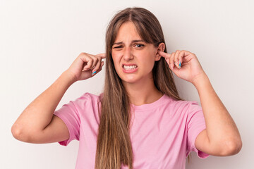 Young caucasian woman isolated on white background covering ears with fingers, stressed and desperate by a loudly ambient.