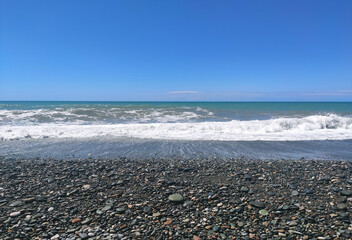 Black sea background with stone beach and waves.