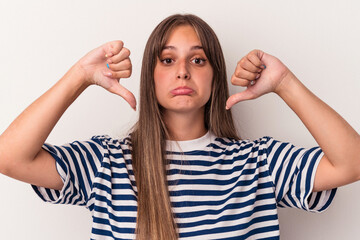 Young caucasian woman isolated on white background showing a dislike gesture, thumbs down....
